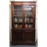 A modern Regency inspired mahogany finished cabinet bookcase, having a level cornice,