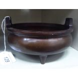 An Oriental cast and patinated bronze censer, the shallow bowl with opposing upstand tab handles,