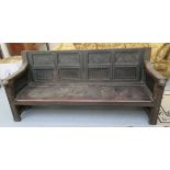 A 19thC oak settle, the angled, panelled, low, level back carved with floral,