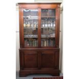 A modern Regency inspired mahogany finished cabinet bookcase, having a level cornice,