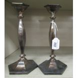 A pair of loaded silver candlesticks of hexagonal outline, each having a shallow vase shaped socket,
