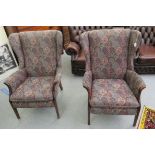 A pair of Parker Knoll wingback chairs with enclosed arms and stained mahogany facings,