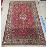 A Persian rug, decorated with stylised floral designs,