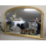 A modern overmantel mirror with an arched top,