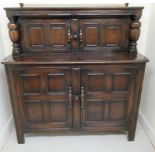 An Ercol dark stained beech court cupboard, the two doors between outset pillars,