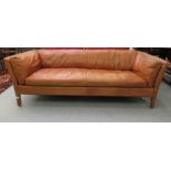 A modern two person settee, having a level back and arms, upholstered in cushioned, soft tan hide,