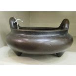 An Oriental cast bronze censer, the shallow, bulbous bowl with opposing upstand tab handles,