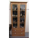 A modern light oak finished cabinet bookcase with a level cornice, over a pair of glazed,