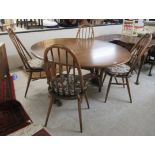 An Ercol Golden Dawn elm drop leaf dining table, the oval top raised on opposing platform feet,