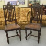 A pair of late Victorian stained and carved oak hall chairs with fruiting vine and foliate ornament,