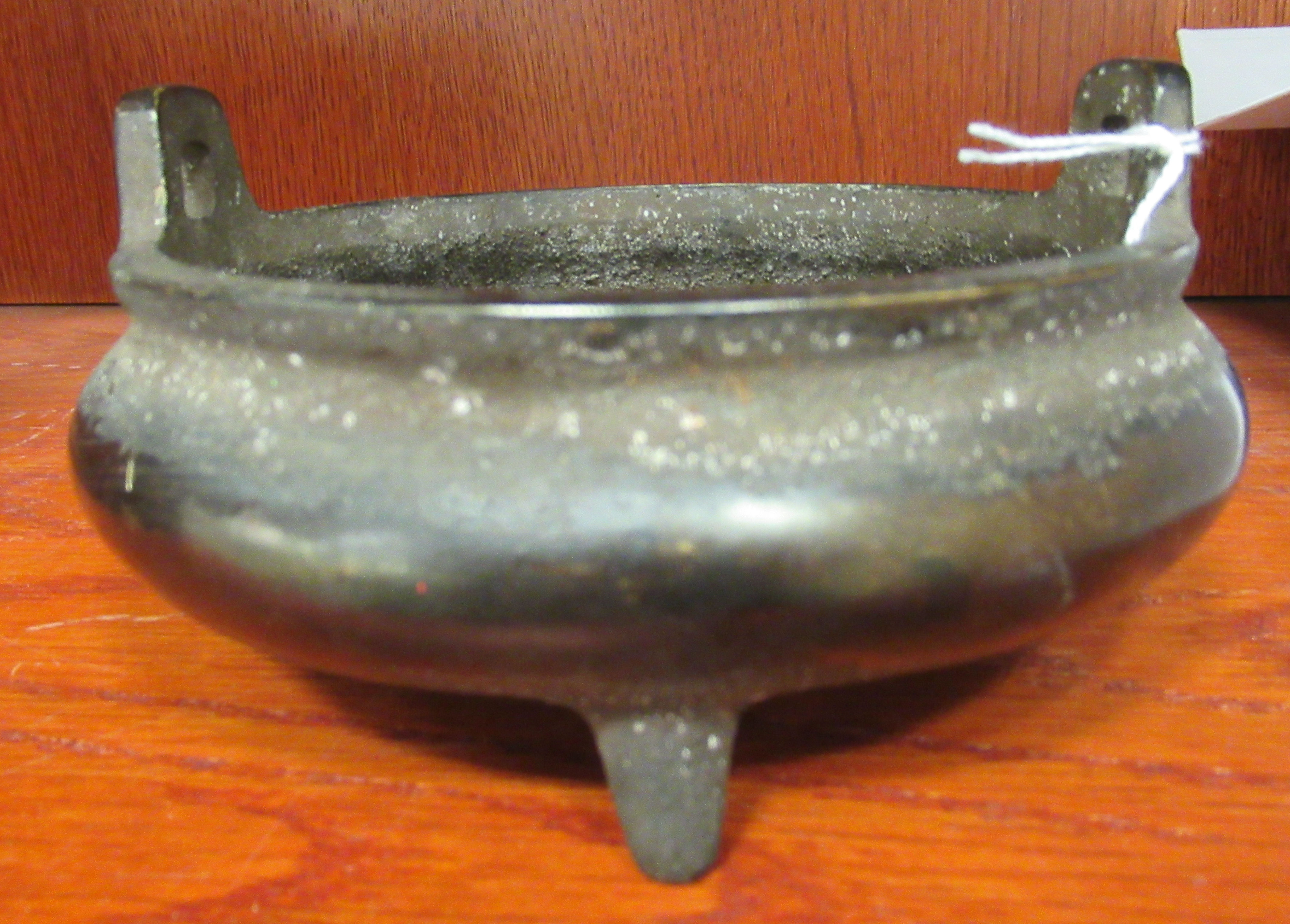 An Oriental cast bronze censer, the shallow, bulbous bowl with opposing handles,