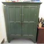 A 20thC green painted cupboard with a dentil moulded cornice, over a pair of panelled doors,