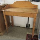 An early 20thC waxed pine washstand with a low back and planked top, raised on ring turned,