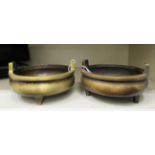 A pair of Oriental cast and patinated bronze censers, the shallow, bulbous bowl with opposing,