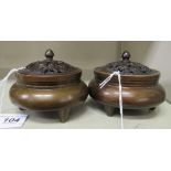 A matched pair of Oriental cast and patinated bronze censers with pierced covers and finials,