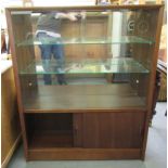 A modern Gibbs Furniture teak bookcase with a pair of glazed doors, enclosing two glazed shelves,