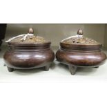 A pair of Oriental cast and patinated bronze censers with pierced covers and finials,