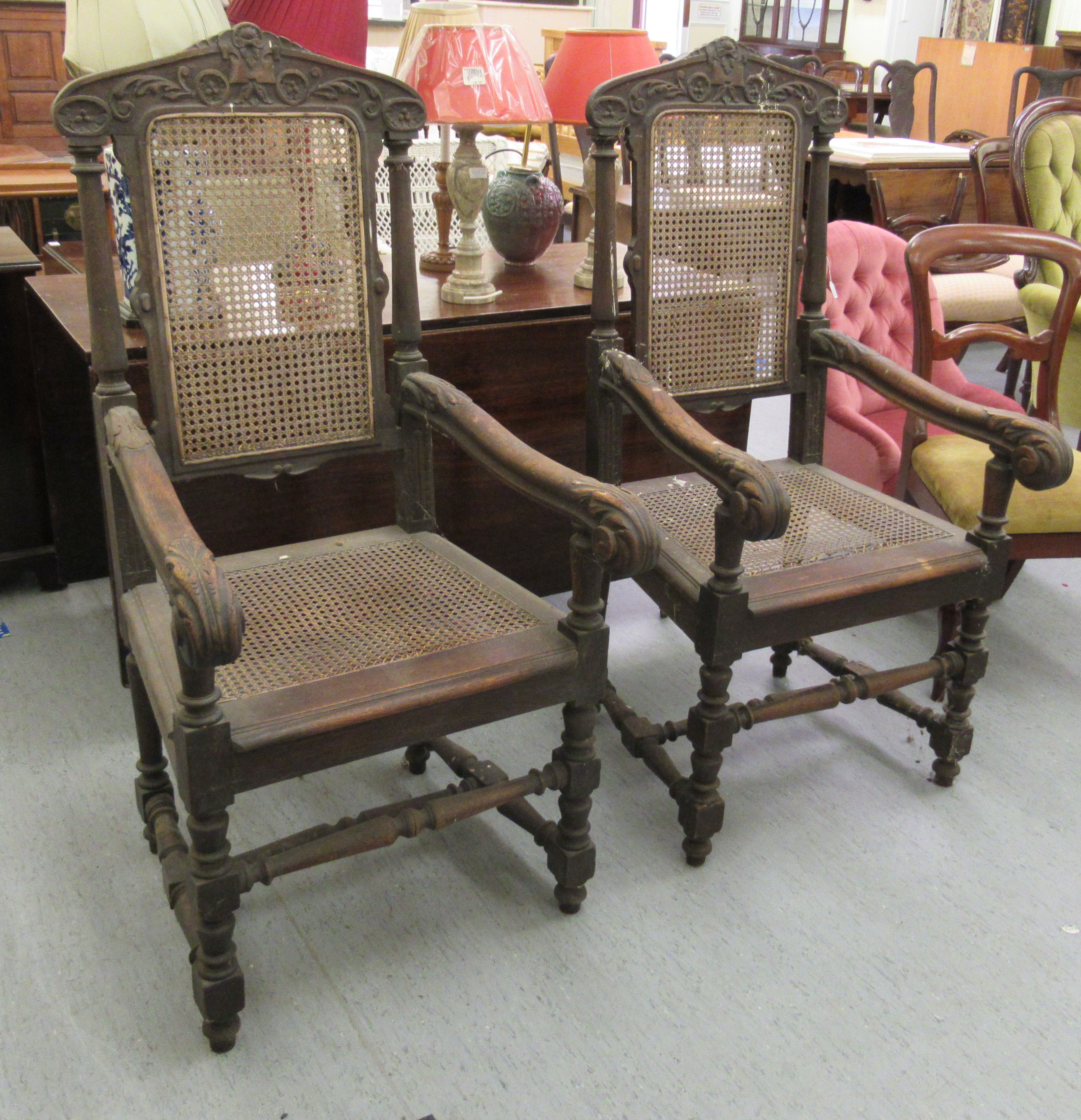 A pair of late 19thC baronial style, oak framed, high back chairs with carved crests, side pillars,