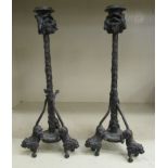 A pair of lacquered cast bronze candlesticks with rams and lions head ornament,