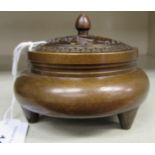 An Oriental cast and patinated bronze censer, having a pierced cover and finial, the shallow,