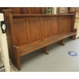 An early 20thC boarded light oak chapel pew, the canopied top acting as a lectern for those behind,