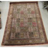 A Persian part silk/part woollen rug, decorated with repeating rectangular panels,