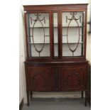 An Edwardian mahogany display cabinet with a pair of glazed doors, over a bow front,