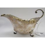 A silver sauce boat with a scrolled handle,