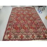 A Persian carpet, decorated with repeating diamond formations, bordered by stylised designs,