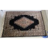 A Persian rug, decorated with an abstract central motif, bordered by floral designs,