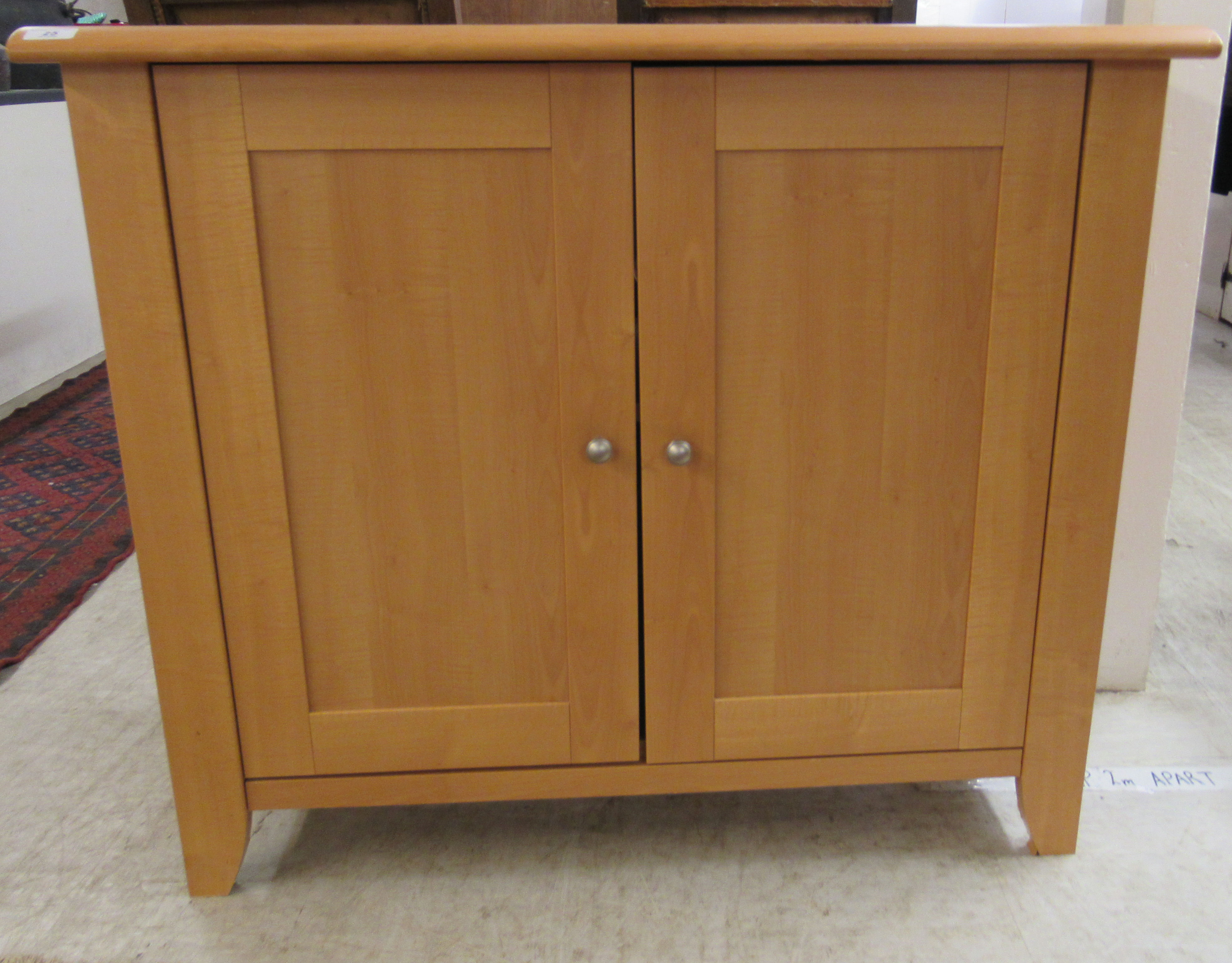 A modern beech cupboard with a pair of doors, enclosing a shelf,