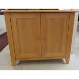 A modern beech cupboard with a pair of doors, enclosing a shelf,