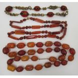 Three dissimilar amber coloured bead necklaces: to include one with interlaced gilt metal ring