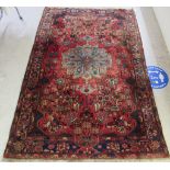 A Persian rug, decorated with repeating stylised floral and other designs,