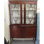 An Edwardian mahogany display cabinet with a pair of glazed doors, over a bow front,