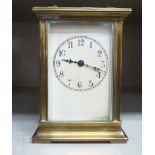 A lacquered brass carriage timepiece with bevelled glass panel and a folding top handles;