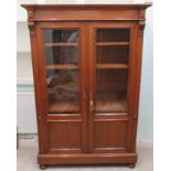 An early 20thC light oak library bookcase with a level cornice, over a pair of full height,