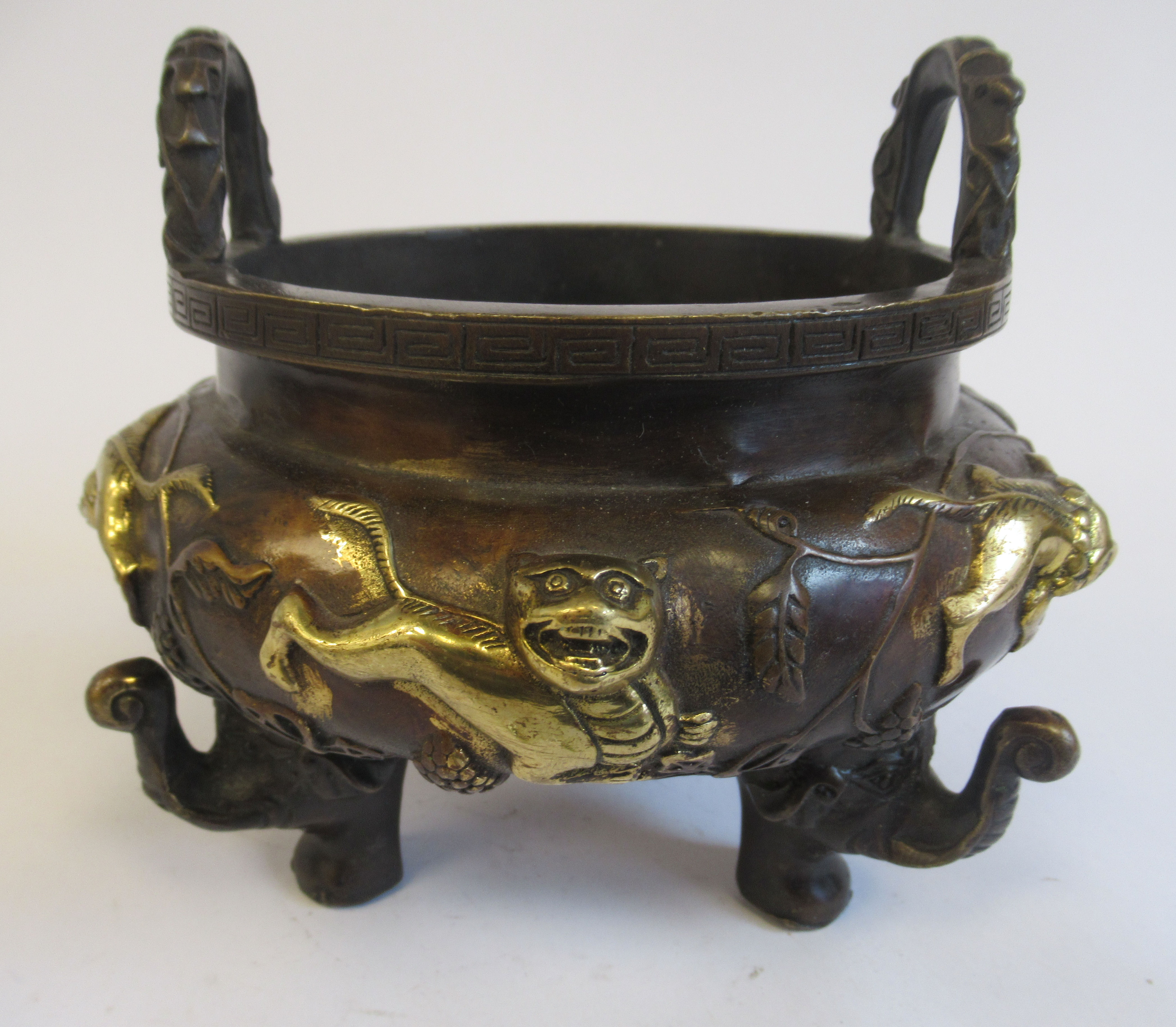 An Oriental cast and patinated and part gilded bronze censer, the bulbous bowl having opposing,