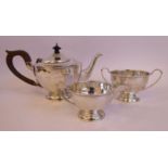 A three piece silver tea set of panelled, circular,