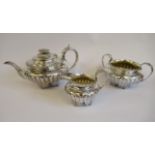 A George IV three piece silver tea set of demi-reeded shallow bowl design with a gadrooned and