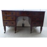 A William IV carved mahogany kneehole desk, the top having a tooled hide scriber,