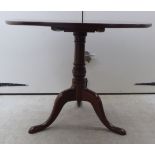 A George III mahogany tip-top pedestal table, raised on a ring turned column,