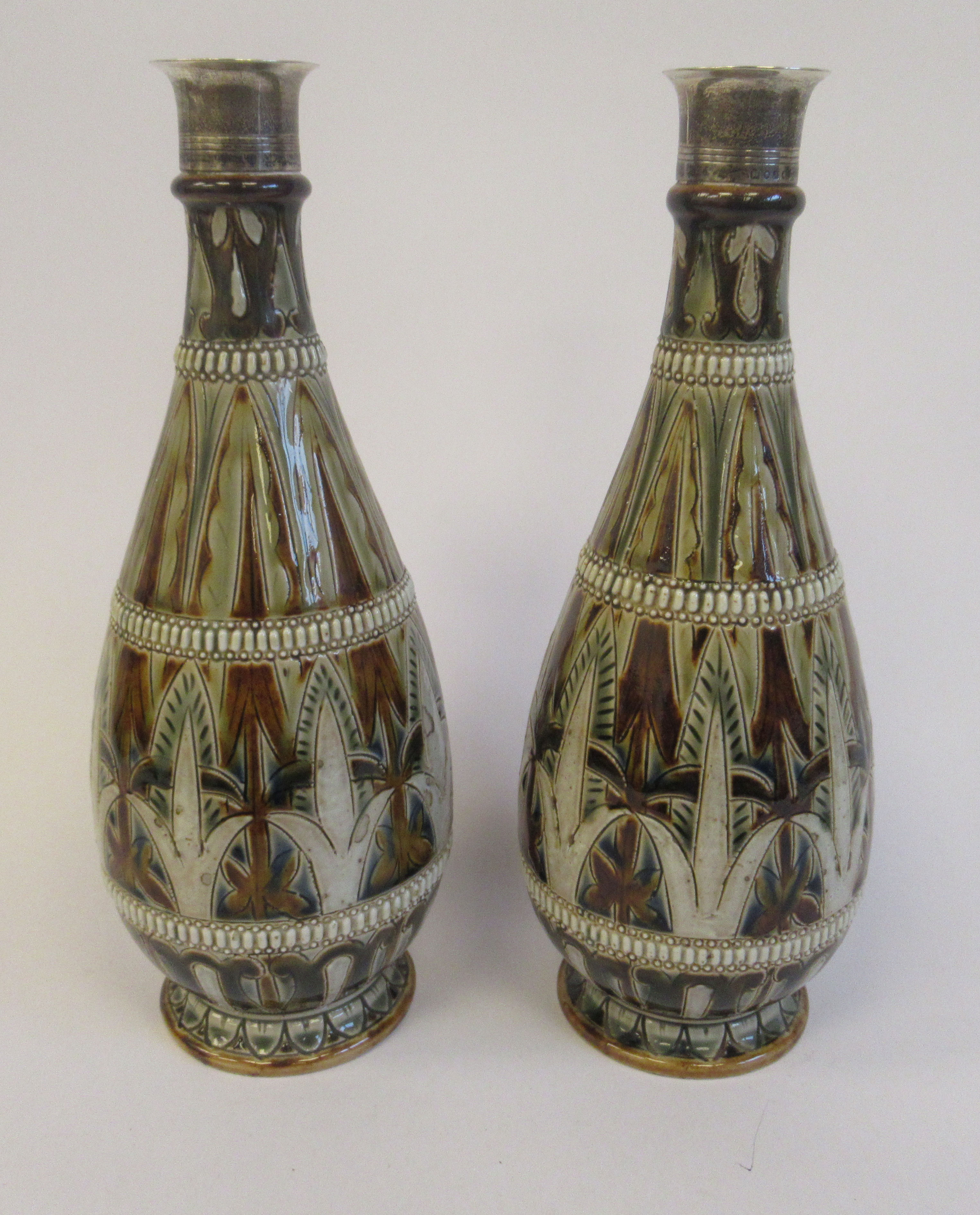 A pair of late Victorian Doulton Lambeth ovoid shaped stoneware bottle vases with applied silver