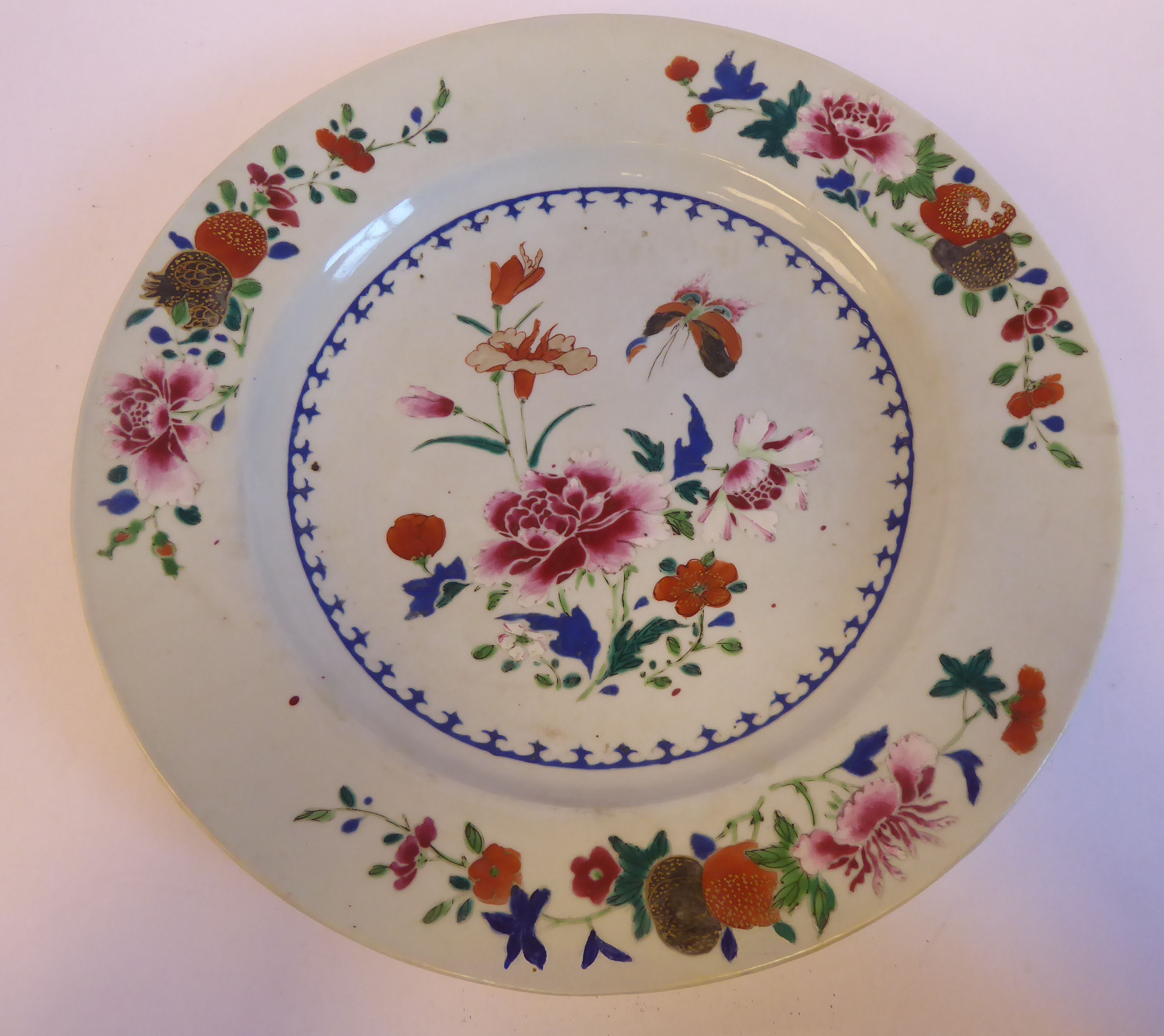 A late 18thC Chinese famille rose, broad rimmed porcelain plate, decorated with flora,