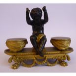 A 19thC cast and part patinated gilt bronze inkstand, featuring a seated cherubic figure,