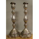 A pair of silver candlesticks with embossed and chased foliate scrolled ornament,