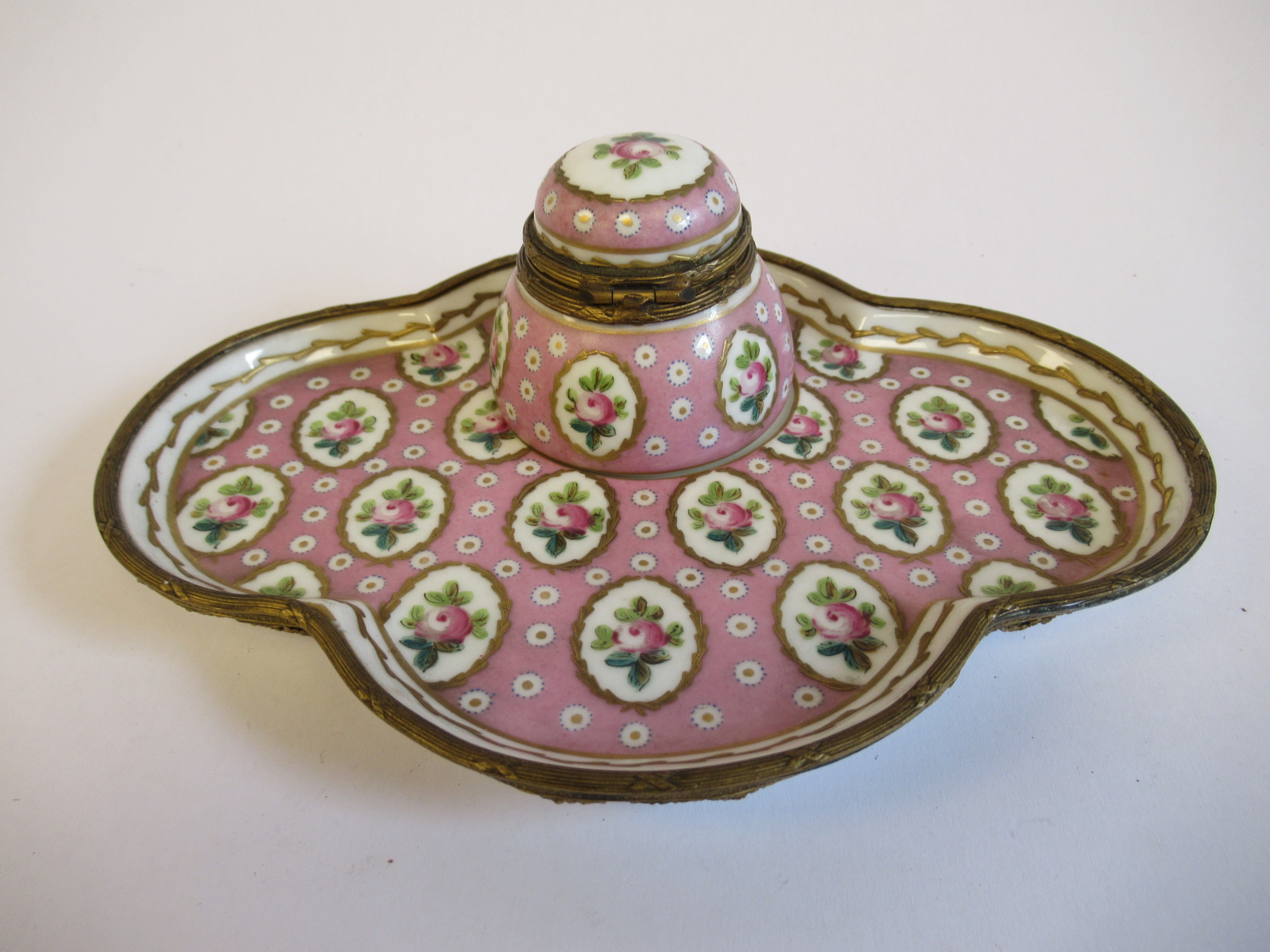 A 19thC Continental gilt metal mounted porcelain inkwell, on a matching, oval, lobed saucer,