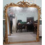 A 19thC round arched overmantel mirror, set in a foliate and floral carved,