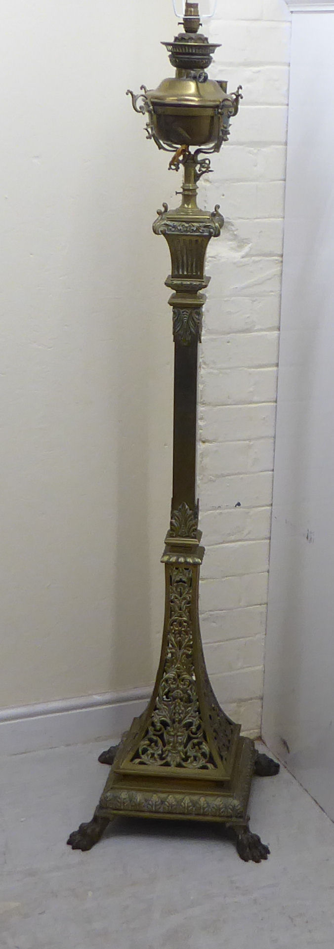 A late Victorian decoratively cast brass, square section lamp standard with a reservoir,