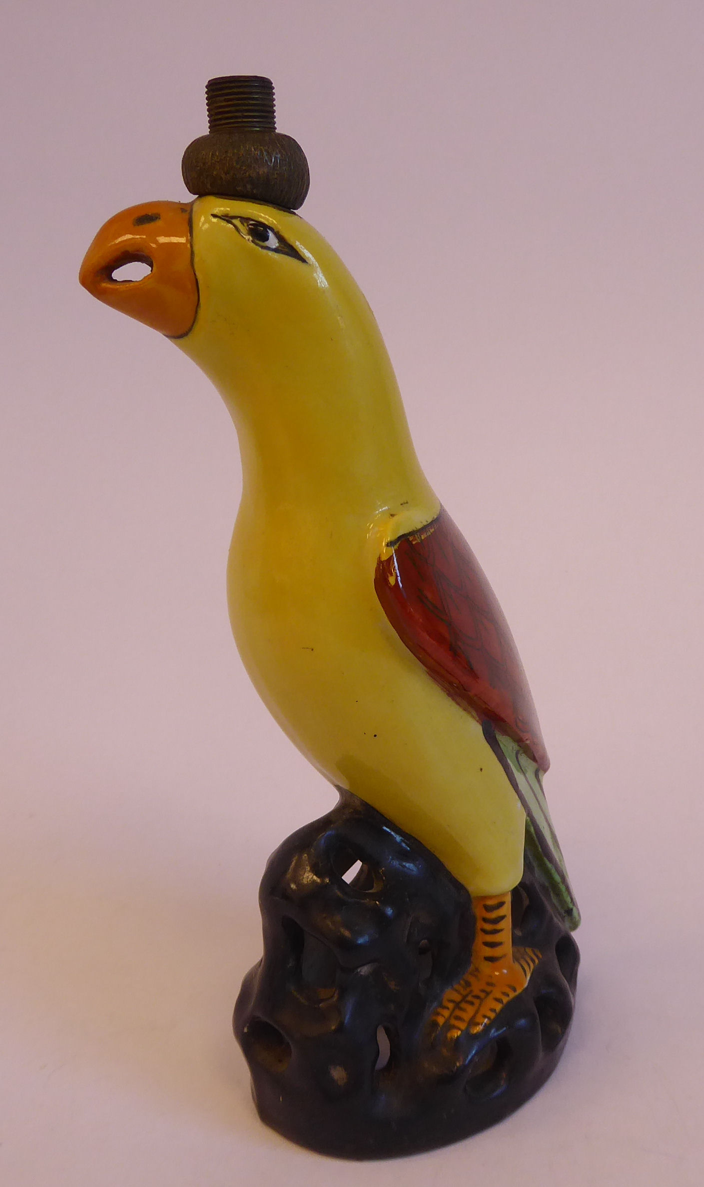 An early 20thC Continental porcelain novelty lamp base, a parrot with yellow and iron red plumage,